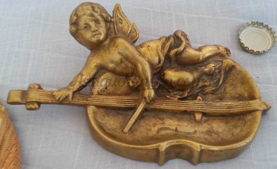 Cenicero en bronce con forma de angelito tocando el violonchelo.