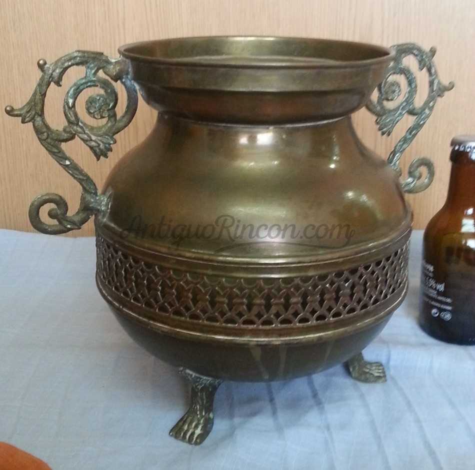 Jarrón vintage en metal dorado con patas en forma de garra de león.