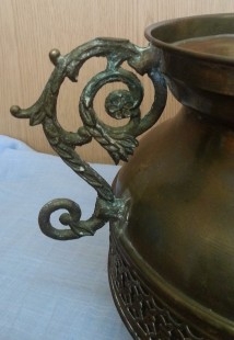 Jarrón vintage en metal dorado con patas en forma de garra de león.