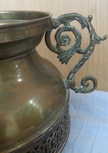 Jarrón vintage en metal dorado con patas en forma de garra de león.