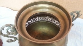 Jarrón vintage en metal dorado con patas en forma de garra de león.