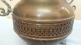 Jarrón vintage en metal dorado con patas en forma de garra de león.