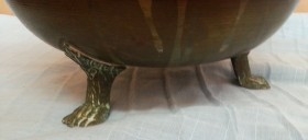 Jarrón vintage en metal dorado con patas en forma de garra de león.