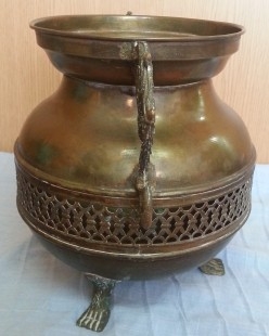 Jarrón vintage en metal dorado con patas en forma de garra de león.