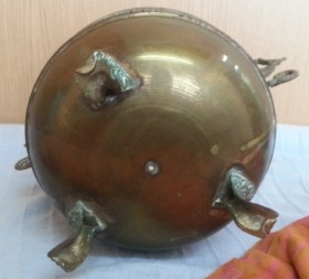 Jarrón vintage en metal dorado con patas en forma de garra de león.