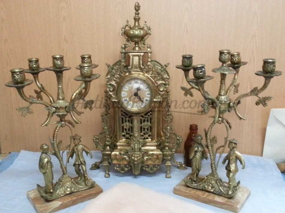 Reloj de mesa y dos candelabros en bronce.