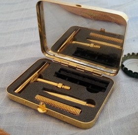 Maquinilla de afeitado en cajita de metal dorada.